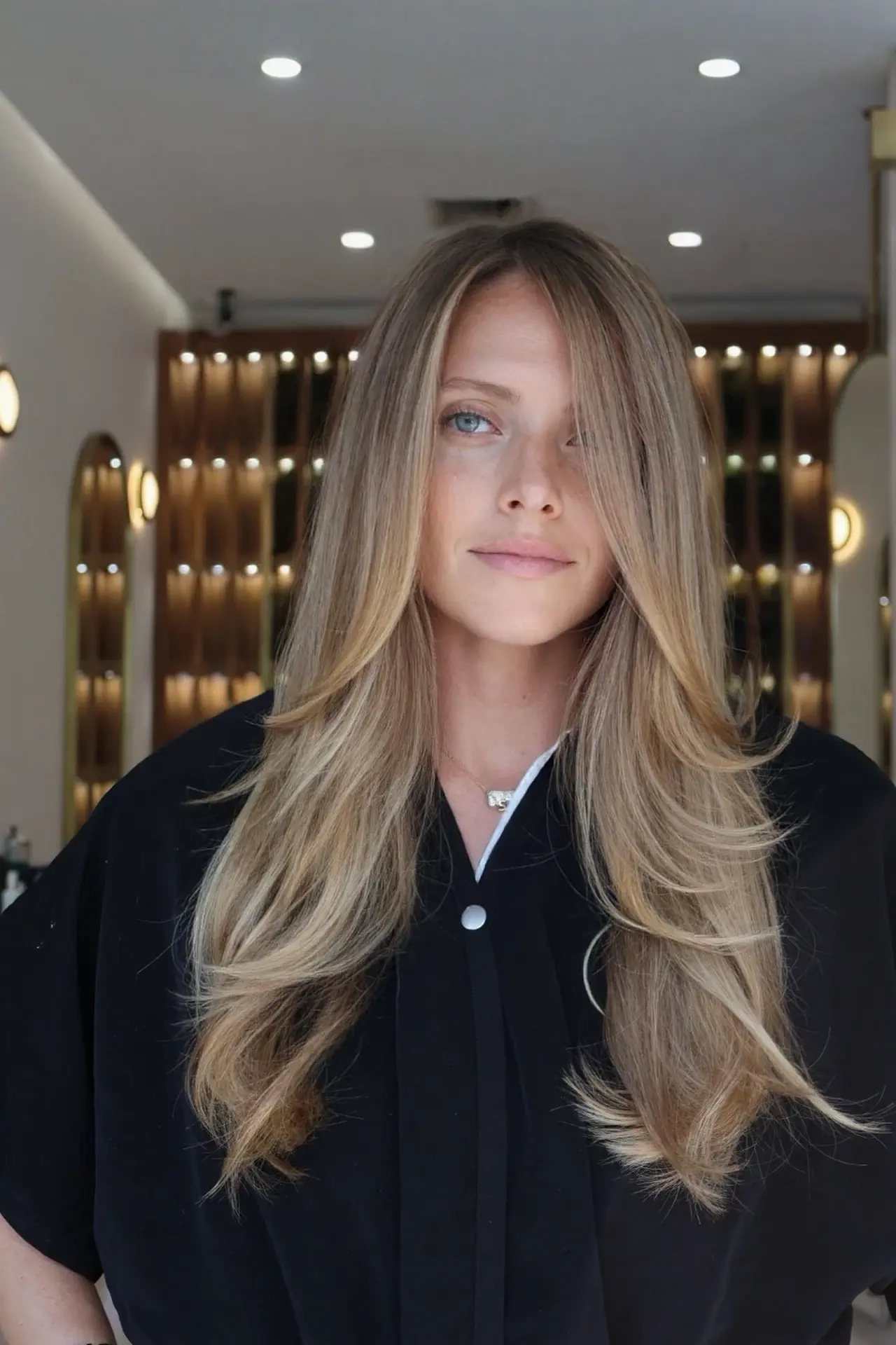 A front view of long dimensional blonde layers sweeping softly around the face at Rové