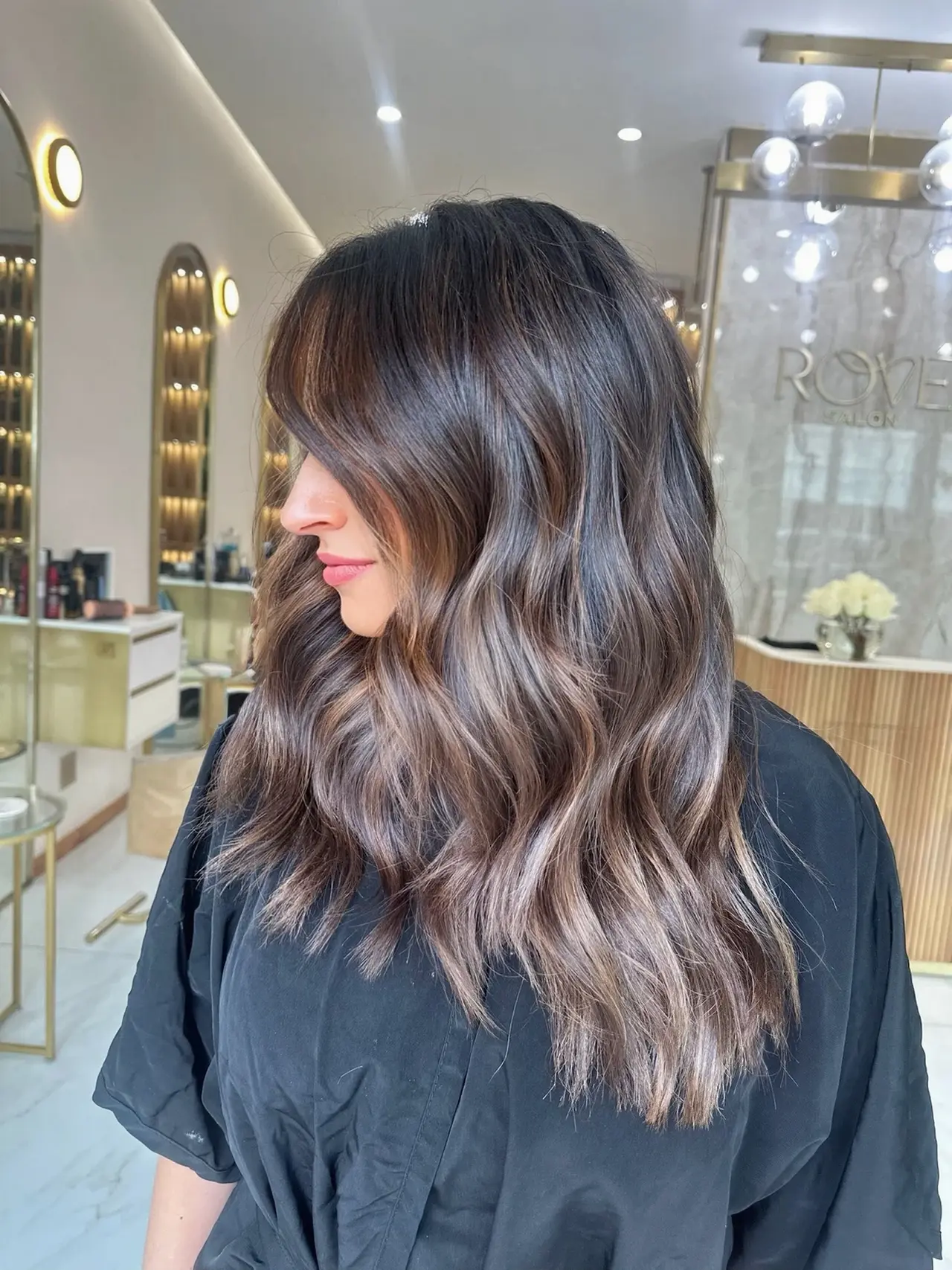 A side view of softly waved brunette hair with beige ribbons through the lengths at Rové