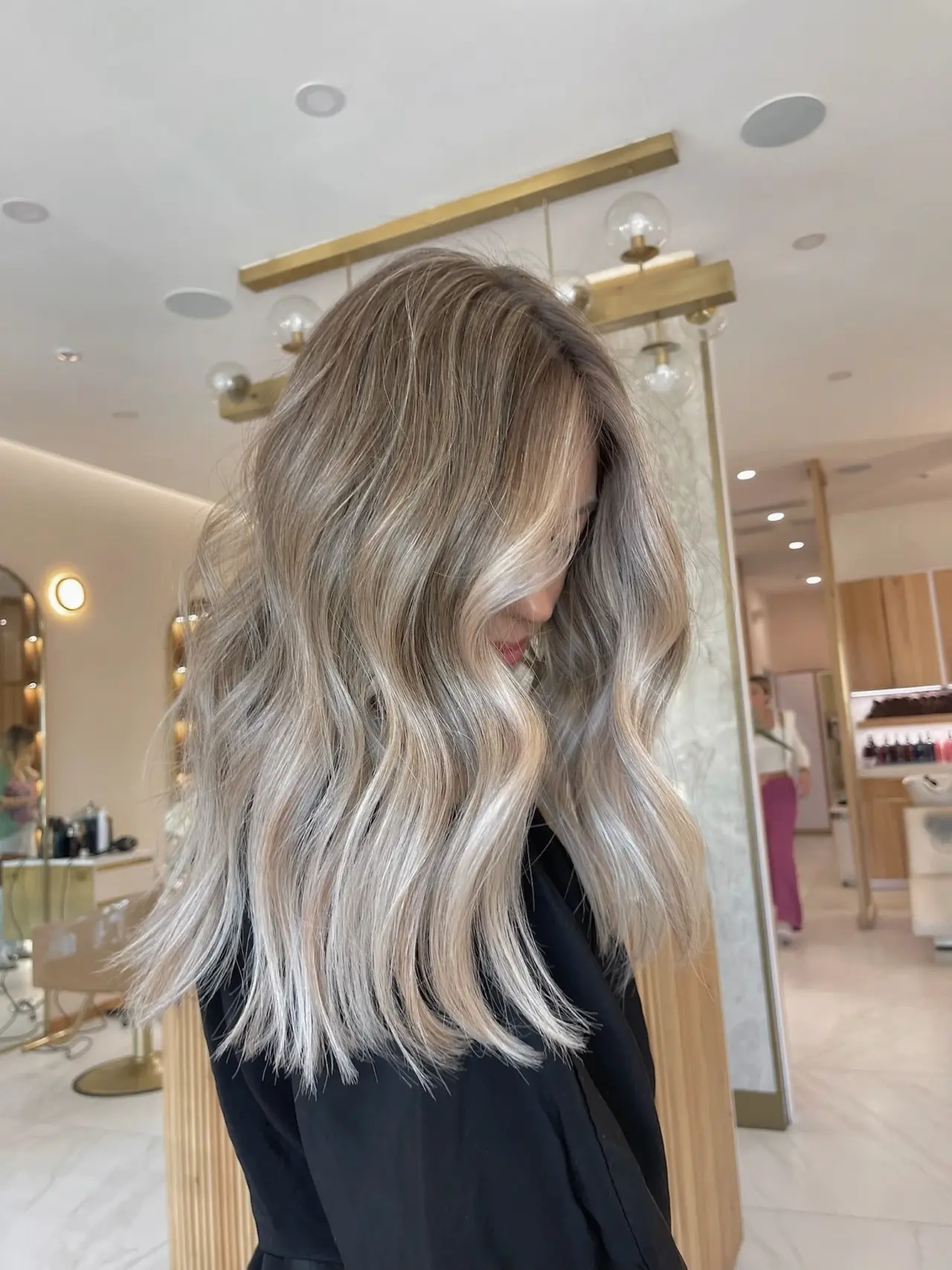 Soft pearl-blonde waves with dimensional roots, photographed from the side at Rové