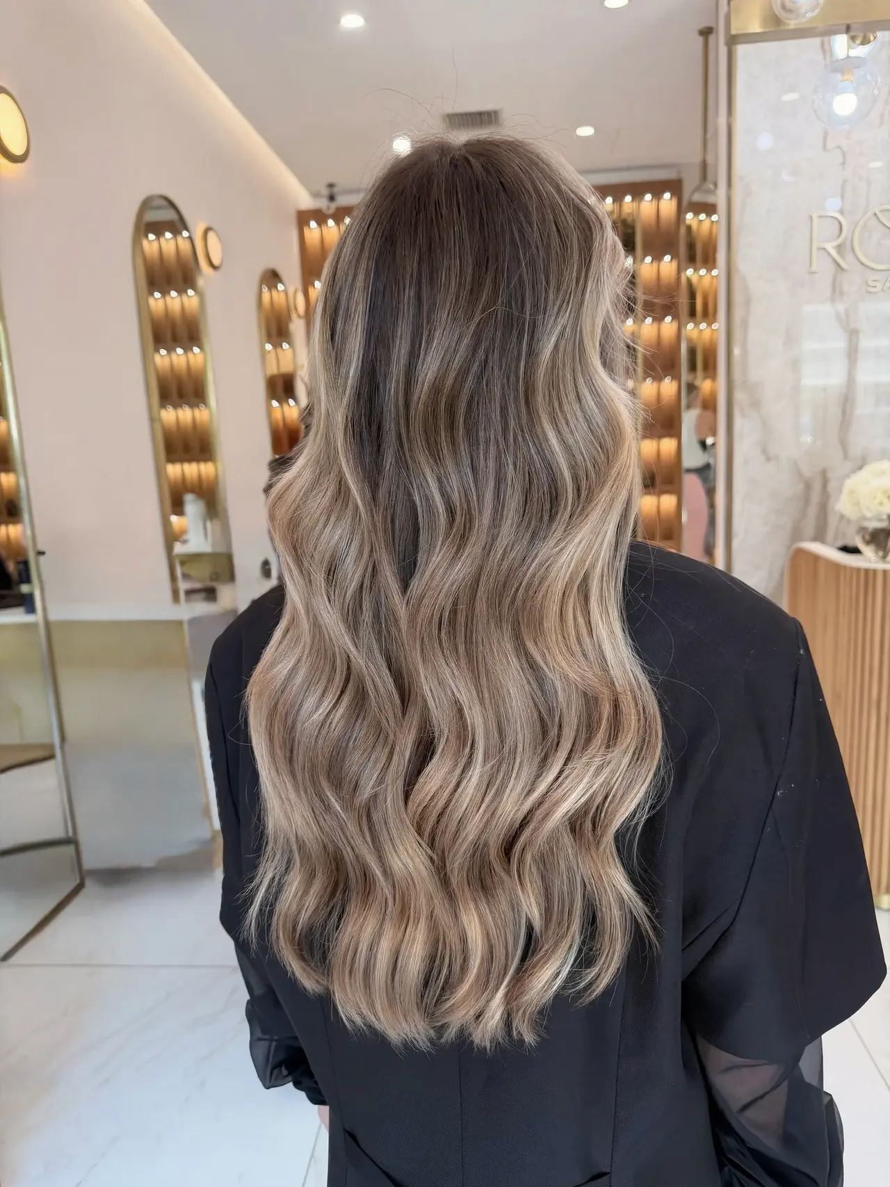 Dimensional dark blonde hair styled in soft waves, seen from behind at Rové