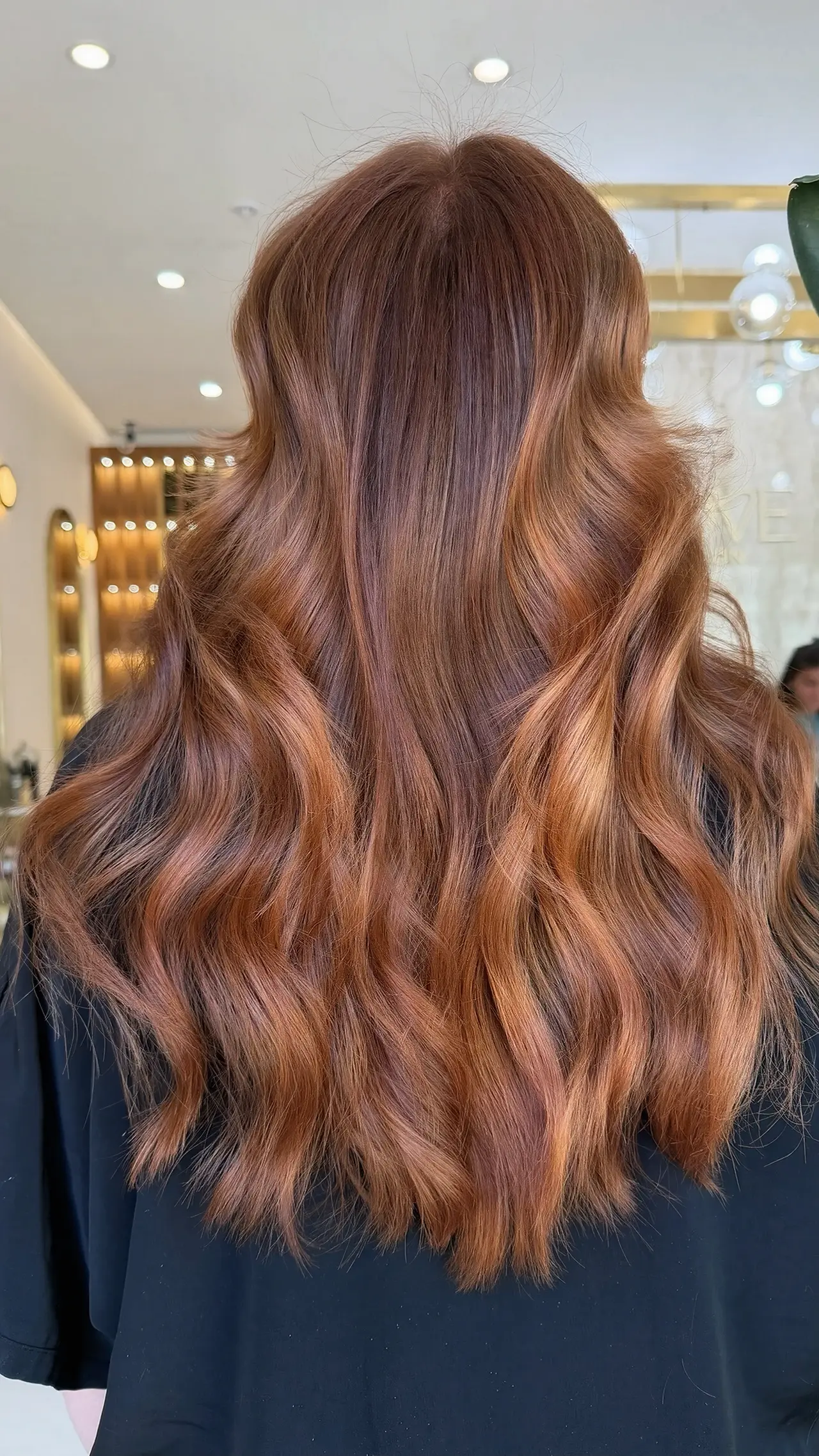 Warm copper waves with a deep root and luminous ends, seen from behind at Rové