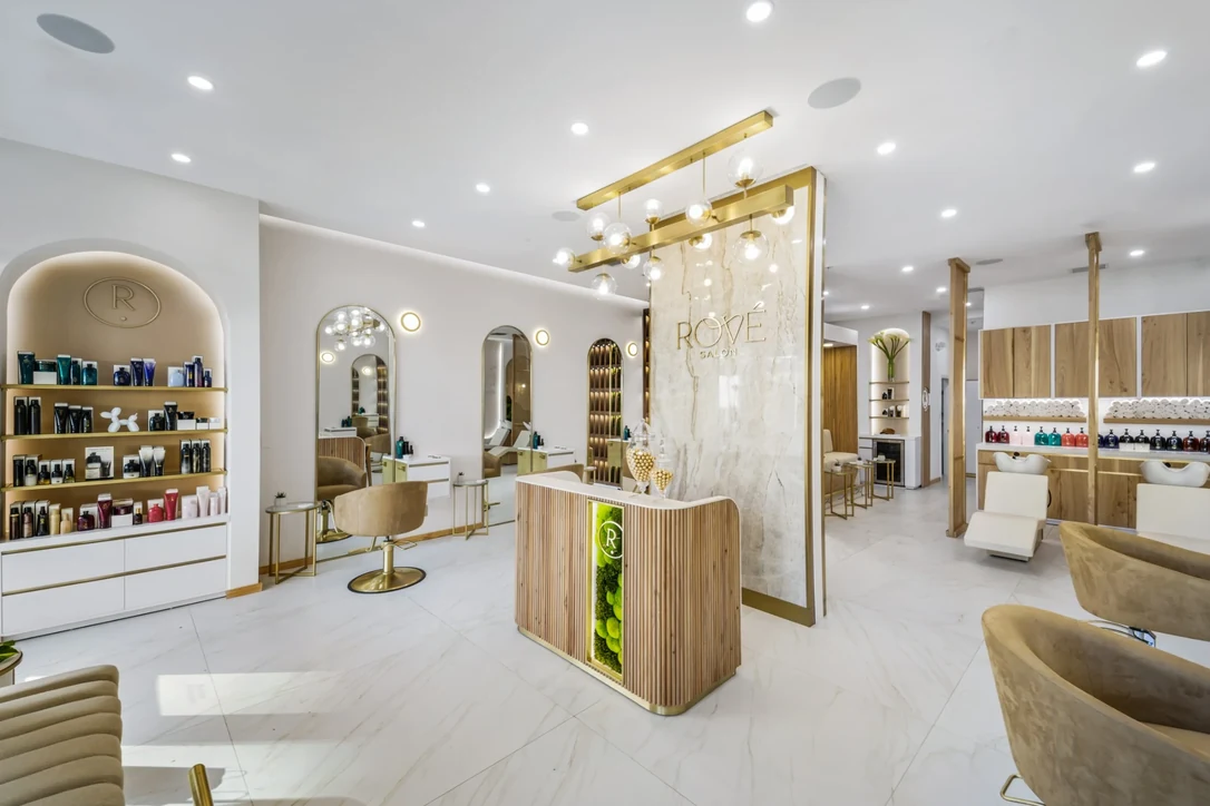 Rové’s oak reception desk, brass mirrors and soft salon seating